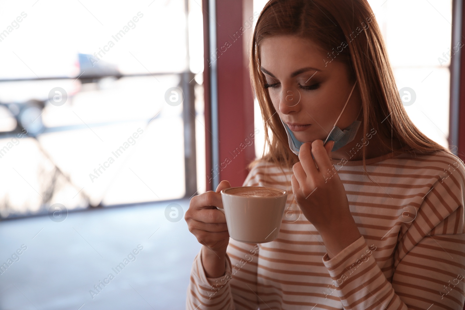 Photo of Woman with medical mask drinking coffee in cafe. Virus protection