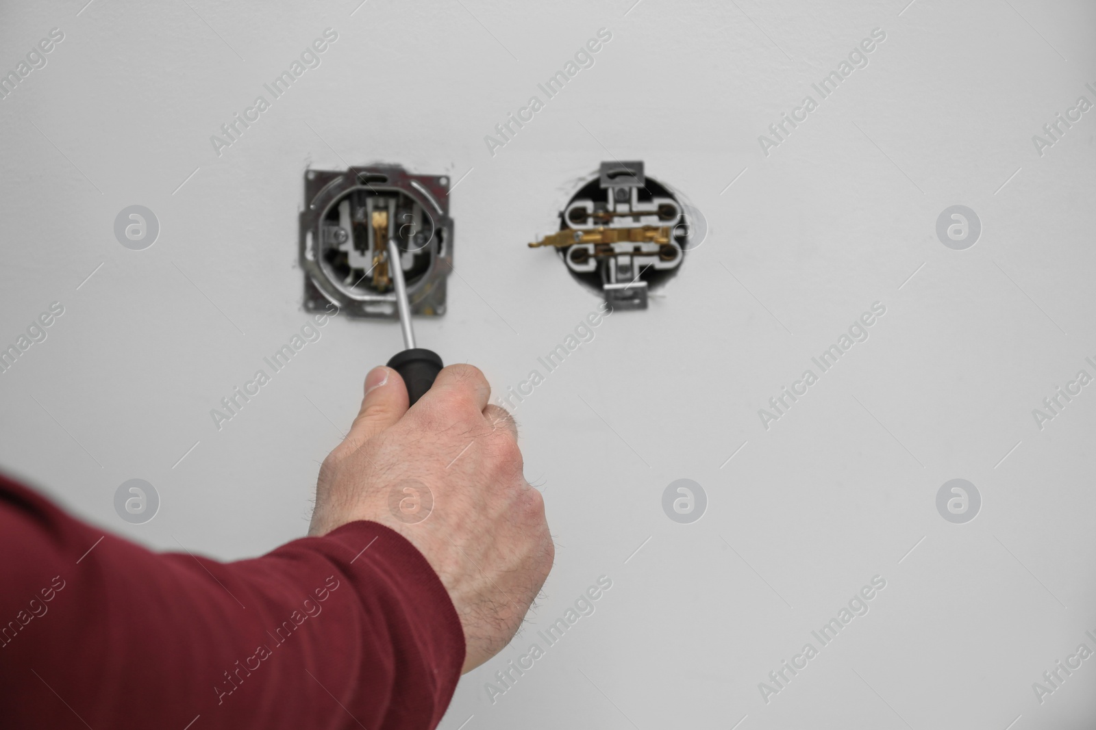 Photo of Electrician repairing wall sockets on white background, closeup