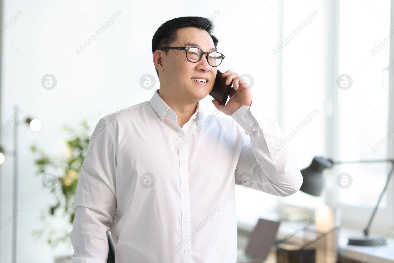 Photo of Portrait of smiling businessman talking by smartphone in office