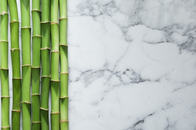 Green bamboo stems and space for text on marble background, top view