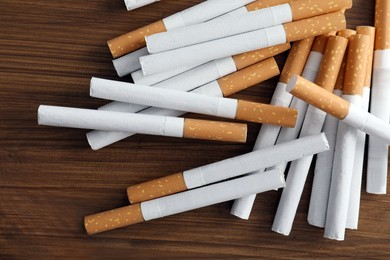 Pile of cigarettes on wooden table, flat lay