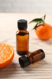Photo of Bottles of tangerine essential oil and fresh fruits on wooden table