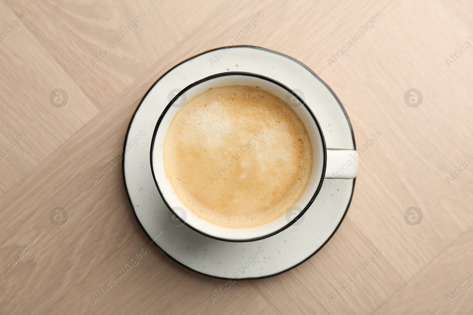 Photo of Tasty cappuccino in cup on light wooden table, top view