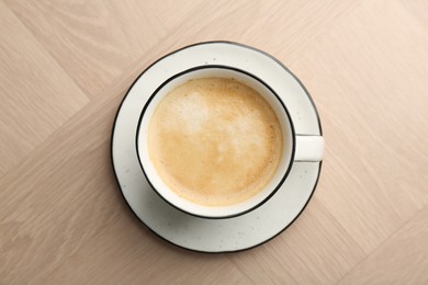 Photo of Tasty cappuccino in cup on light wooden table, top view