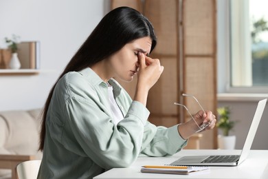 Photo of Young woman suffering from eyestrain at desk in office