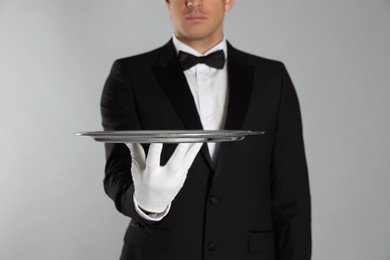 Photo of Butler with tray on light grey background, closeup
