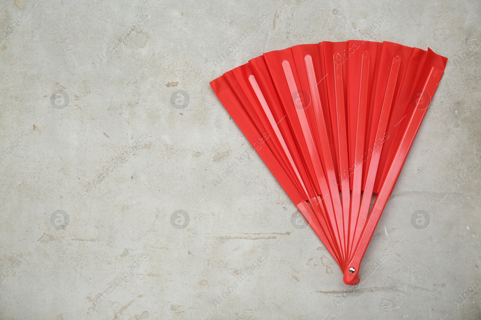 Photo of Bright red hand fan on old light grey background, top view. Space for text