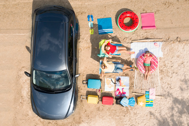 Family with beach accessories and car near river, aerial view. Summer trip