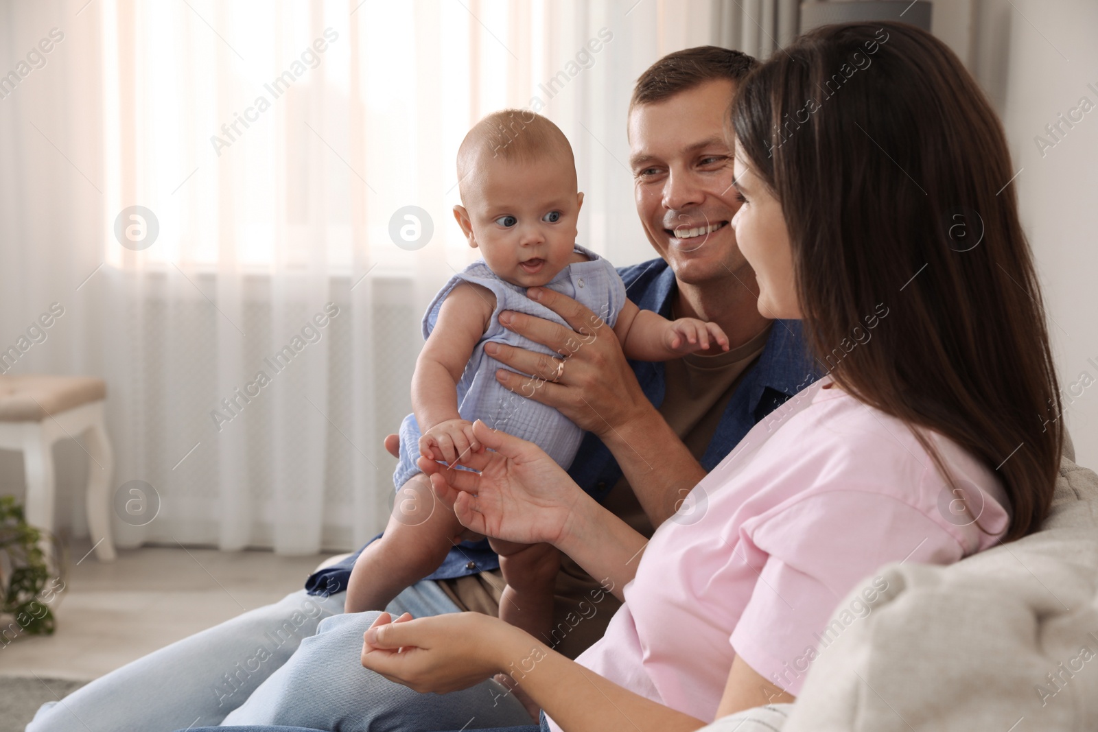 Photo of Happy family with their cute baby on sofa in living room