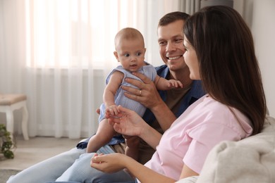 Photo of Happy family with their cute baby on sofa in living room