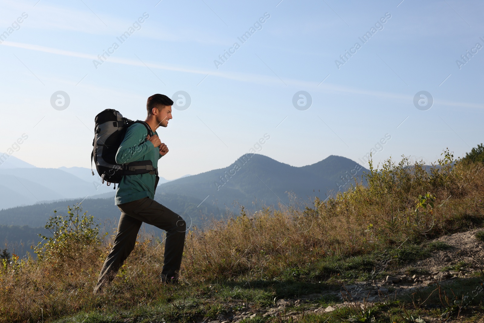 Photo of Tourist with backpack in mountains on sunny day. Space for text