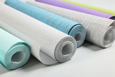 Photo of Different stylish wallpaper rolls on light background, closeup