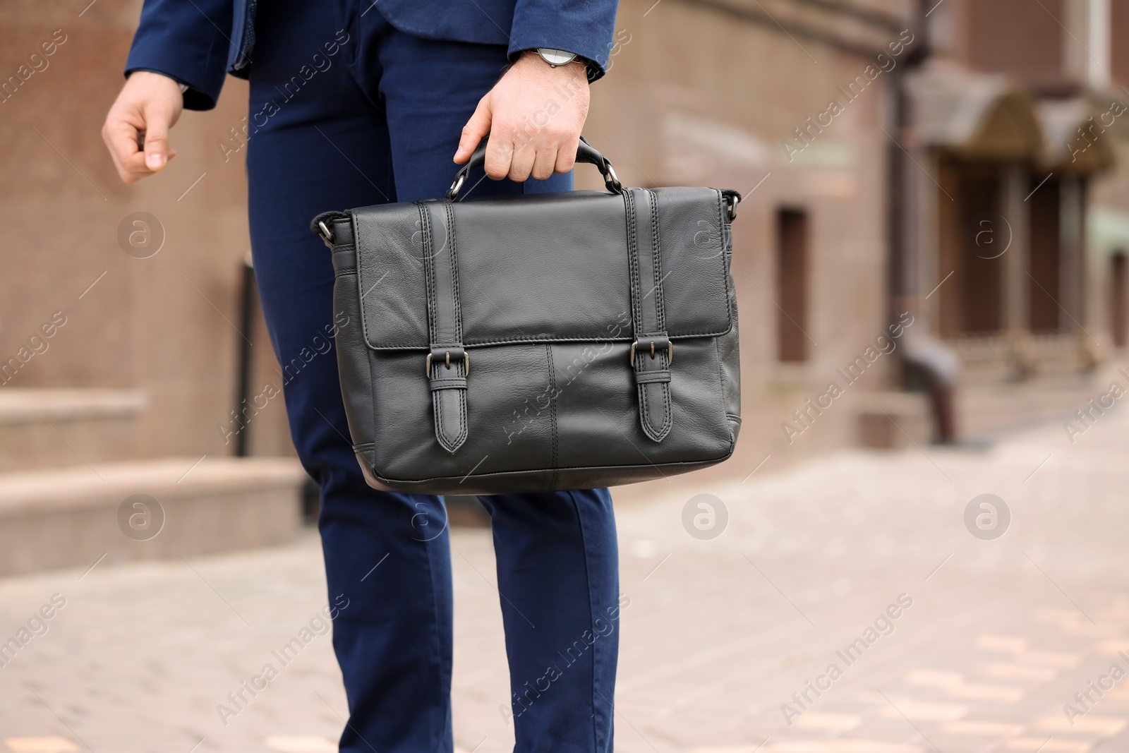 Photo of Businessman with black briefcase in hand outdoors. Space for text