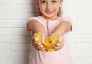 Photo of Little girl with slime near white brick wall