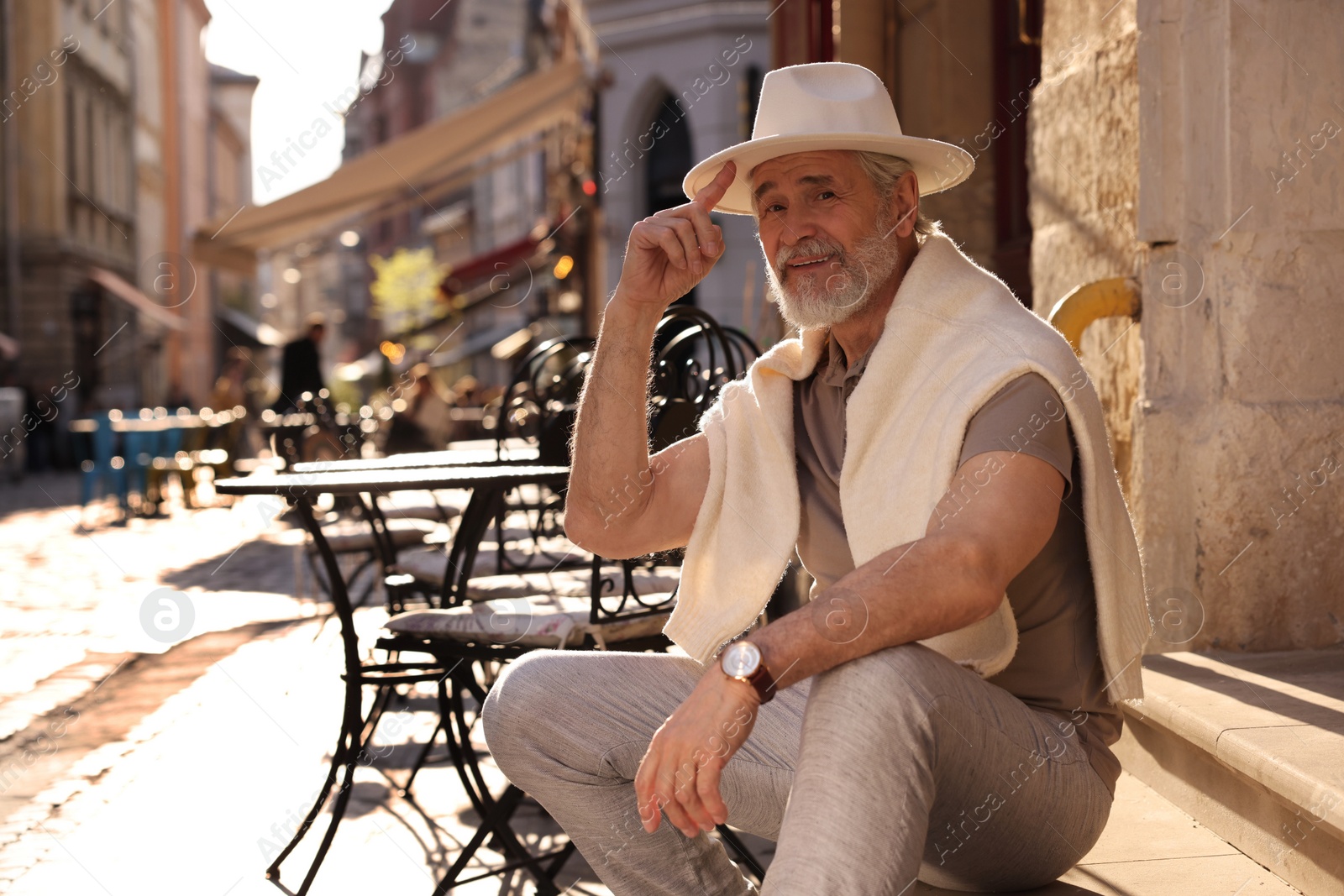 Photo of Handsome senior man sitting on doorstep outdoors, space for text