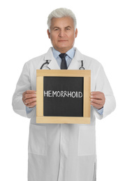Photo of Doctor holding blackboard with word HEMORRHOID on white background