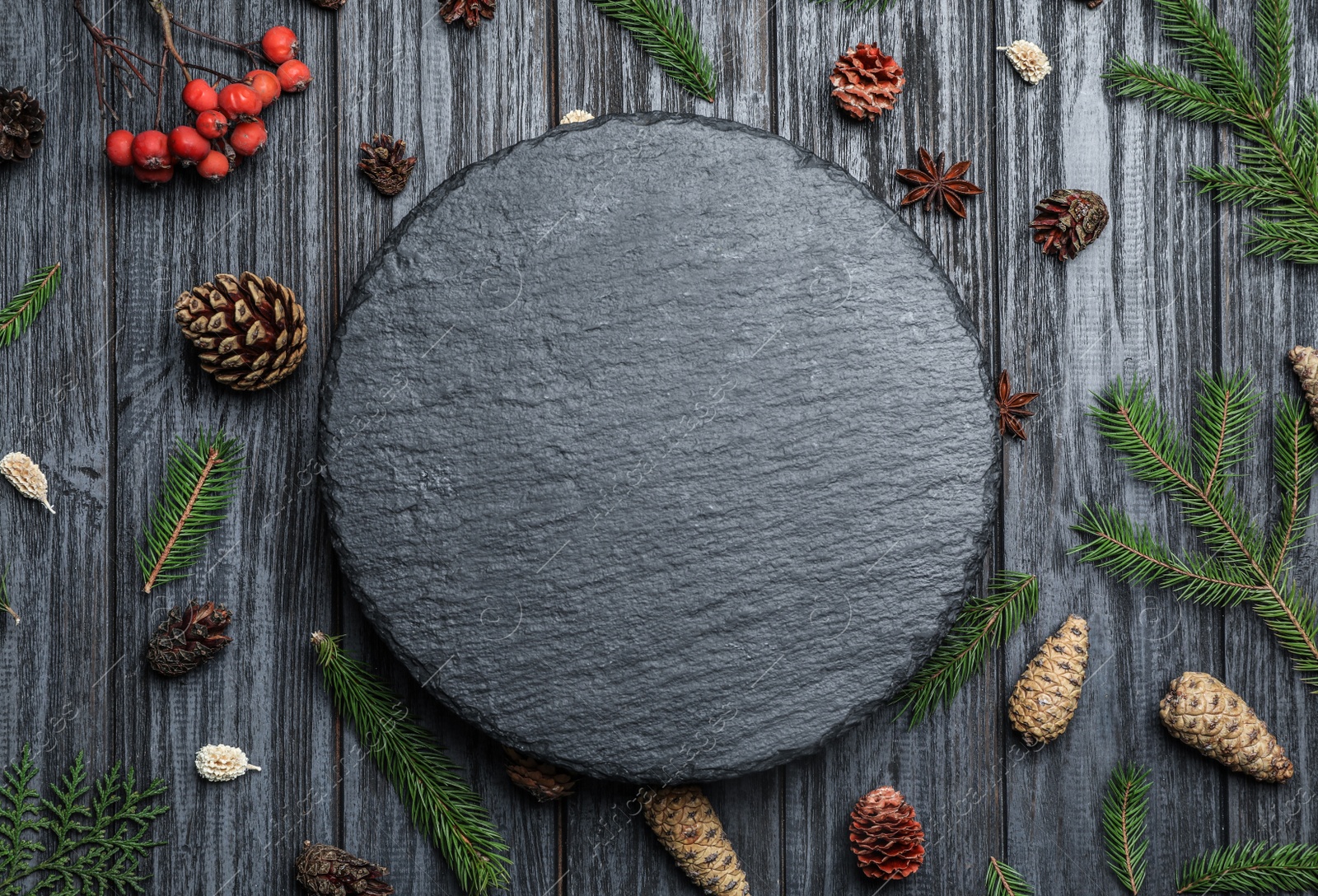 Photo of Flat lay composition with pinecones and slate board on black wooden background, space for text