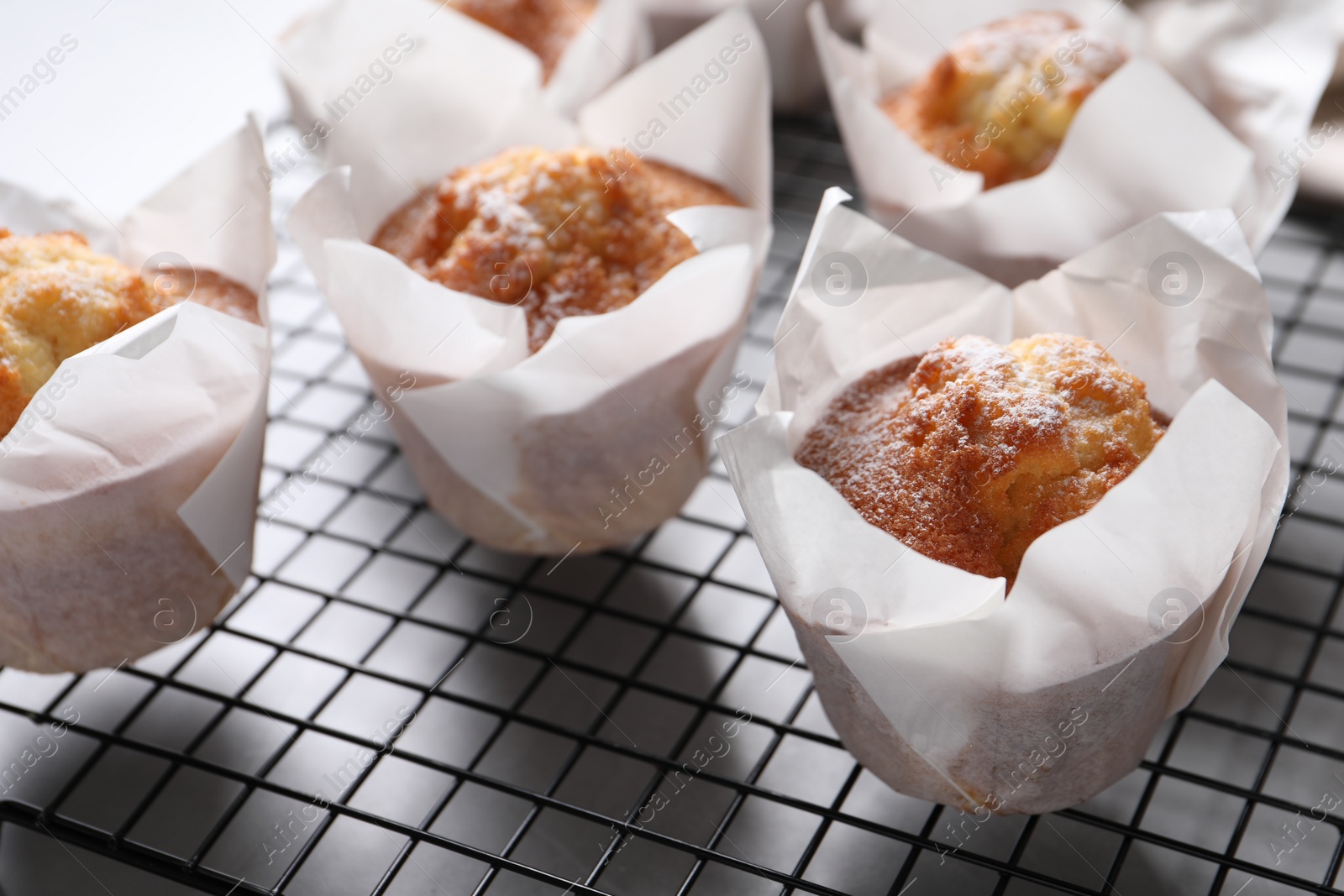 Photo of Delicious muffins with powdered sugar on light table, closeup