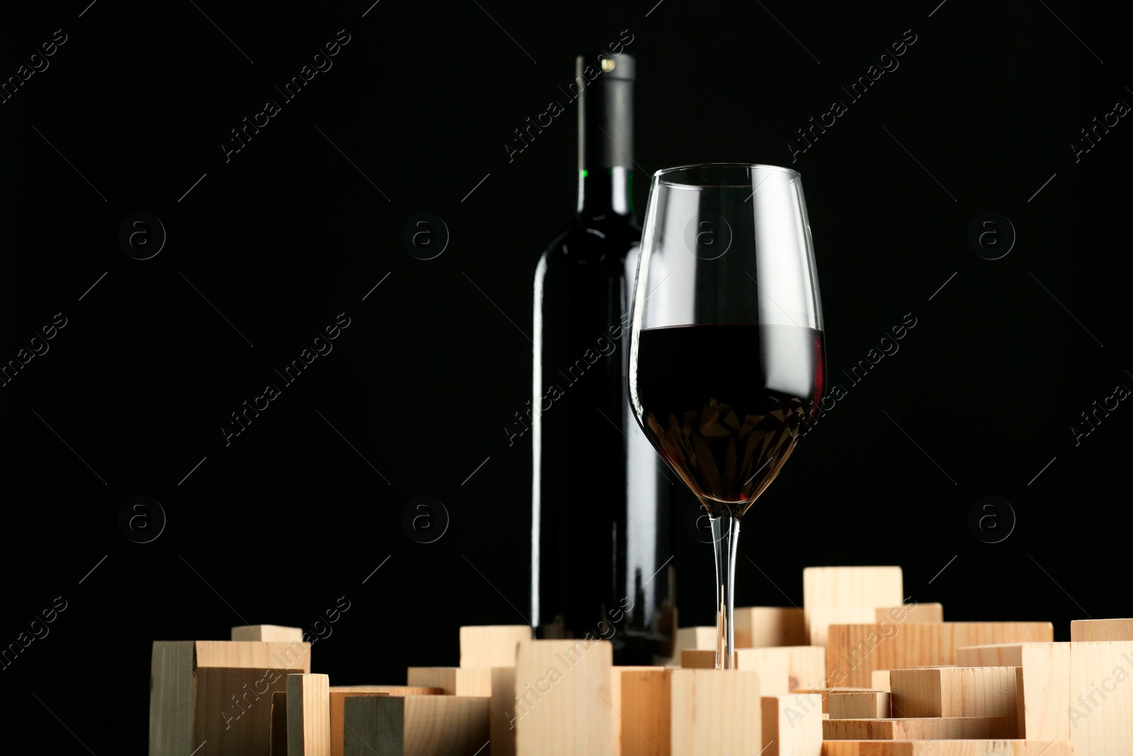 Photo of Stylish presentation of red wine in bottle and wineglass on black background