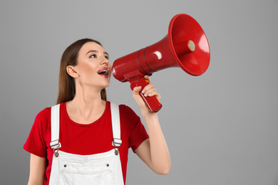 Photo of Young woman with megaphone on light grey background