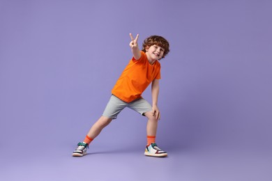 Photo of Happy little boy dancing on violet background