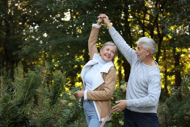 Photo of Affectionate senior couple dancing together outdoors, space for text