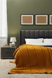 Photo of Large comfortable bed, nightstand and lamp in stylish room. Interior design
