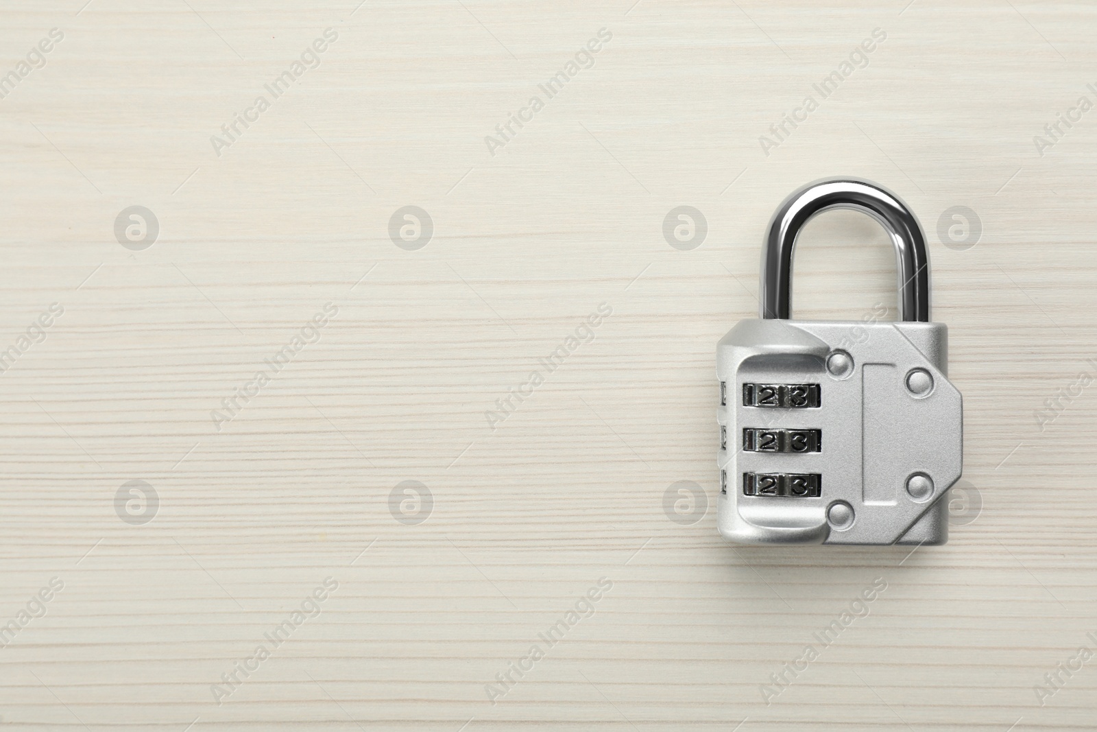 Photo of Modern combination lock on white wooden table, top view. Space for text