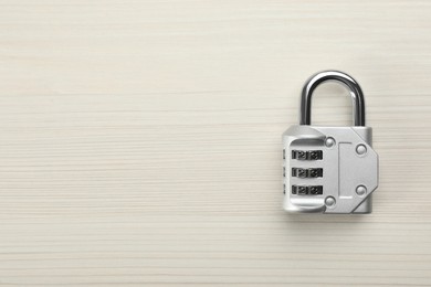 Photo of Modern combination lock on white wooden table, top view. Space for text