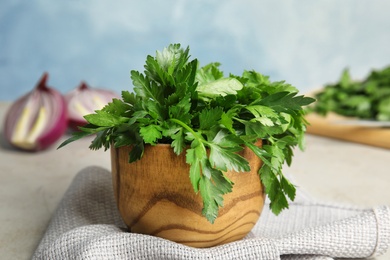 Photo of Wooden bowl with fresh green parsley on table
