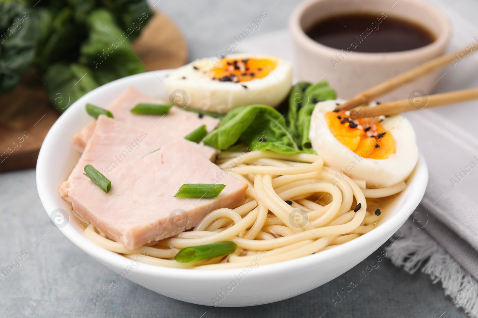 Photo of Delicious ramen with meat on light grey table, closeup. Noodle soup