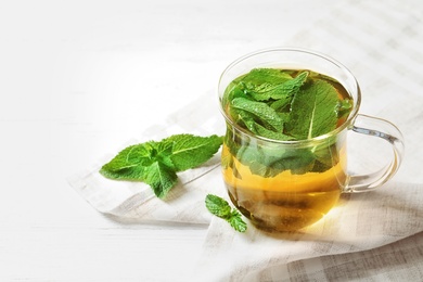 Photo of Cup with hot aromatic mint tea on table