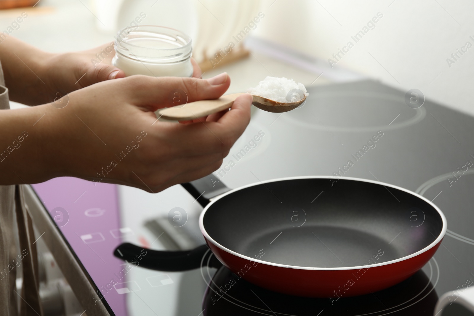 Photo of Woman cooking with coconut oil on induction stove, closeup