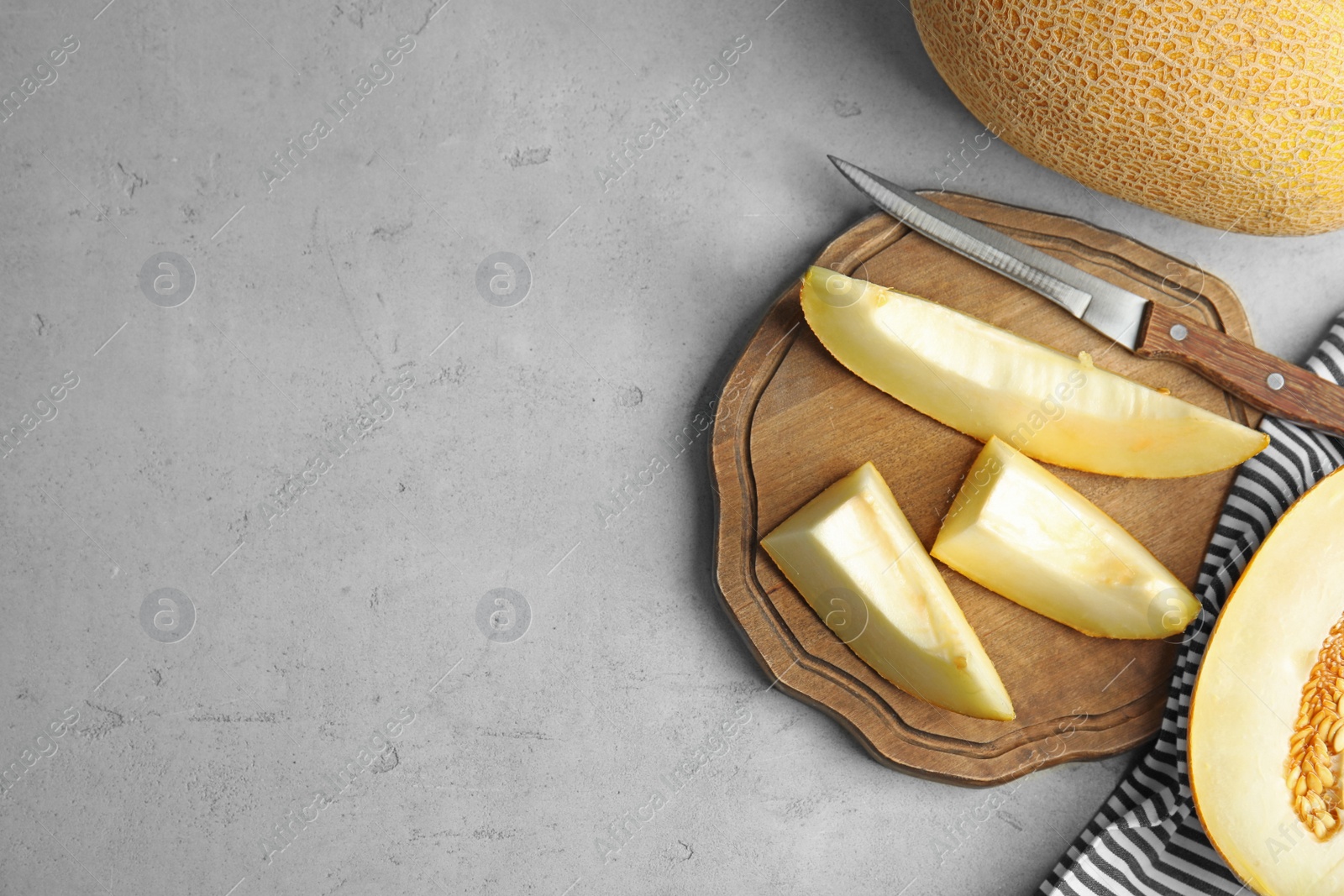 Photo of Flat lay composition with ripe melons on grey table. Space for text