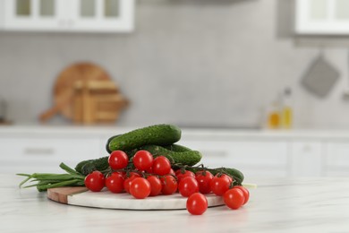 Fresh clean vegetables on white table in kitchen, space for text