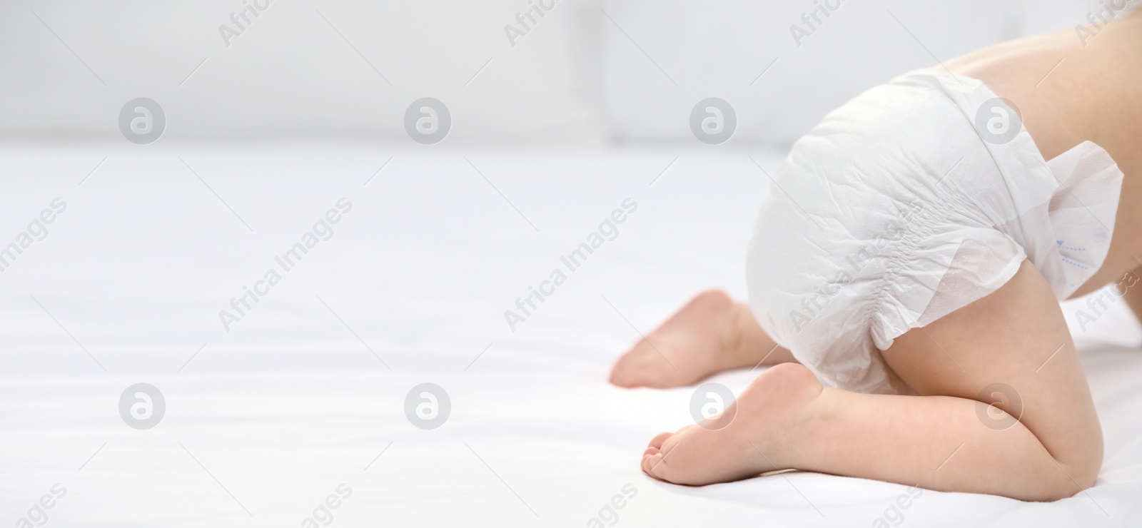 Image of Cute little baby in diaper on bed, closeup. Banner design with space for text