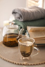 Photo of Glass teapot and cup of hot tea on table in room. Cozy home atmosphere