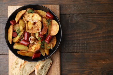 Photo of Delicious baked potato with thin dry smoked sausages in bowl and bread on wooden table, top view. Space for text