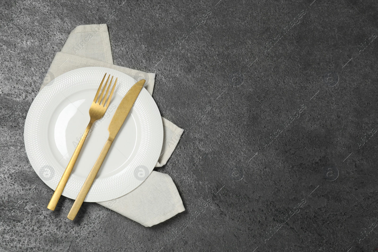 Photo of Stylish setting with elegant cutlery on grey table, top view. Space for text