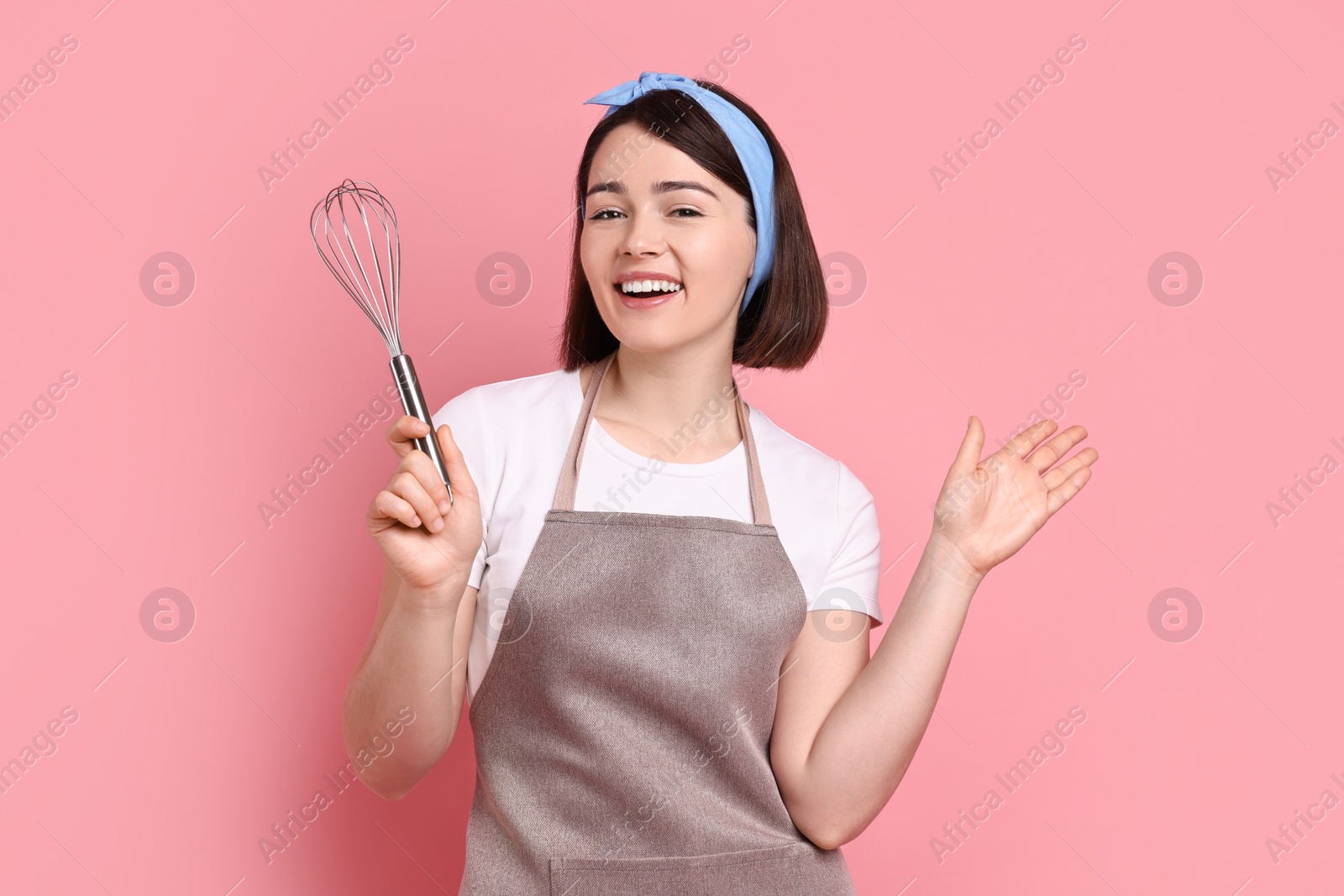 Photo of Happy confectioner with whisk on pink background