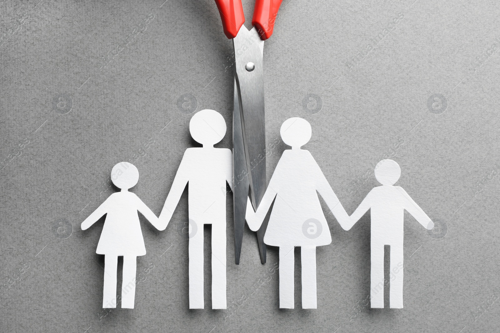 Photo of Divorce concept. Paper cutout of family and scissors on light grey background, flat lay