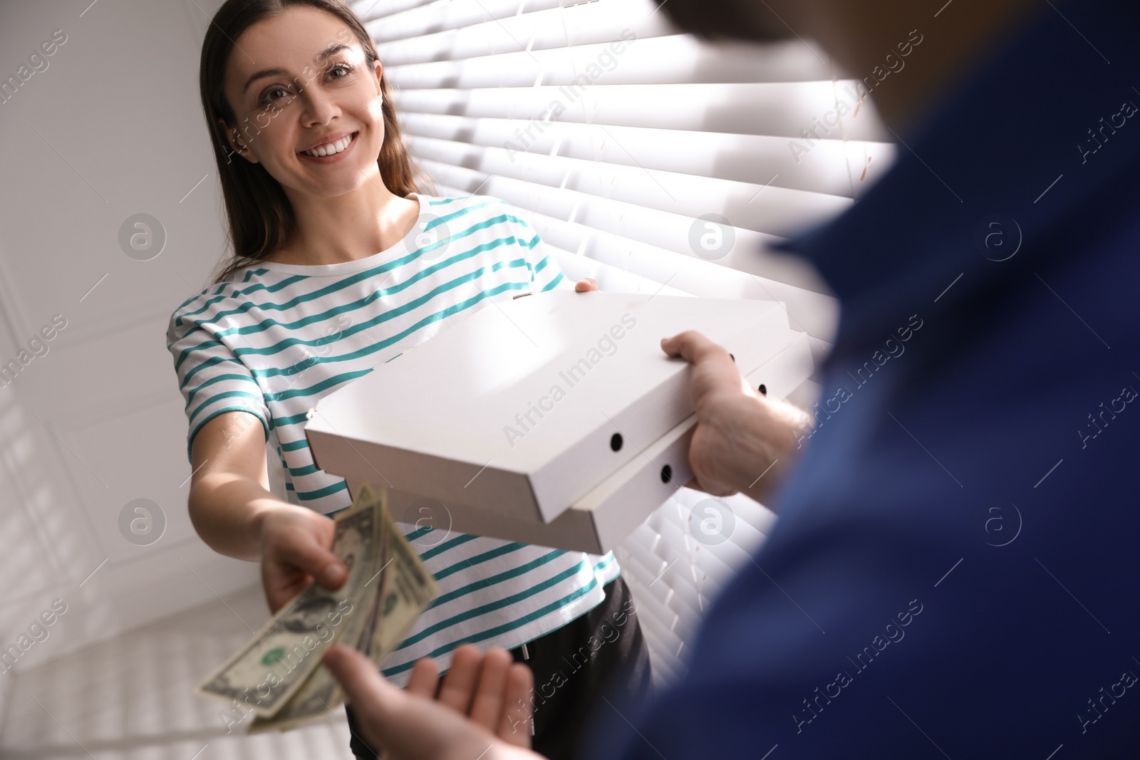 Photo of Young woman giving tips to deliveryman indoors