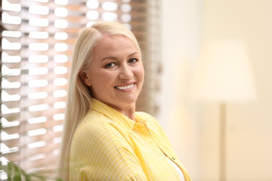 Photo of Portrait of happy mature woman near window indoors