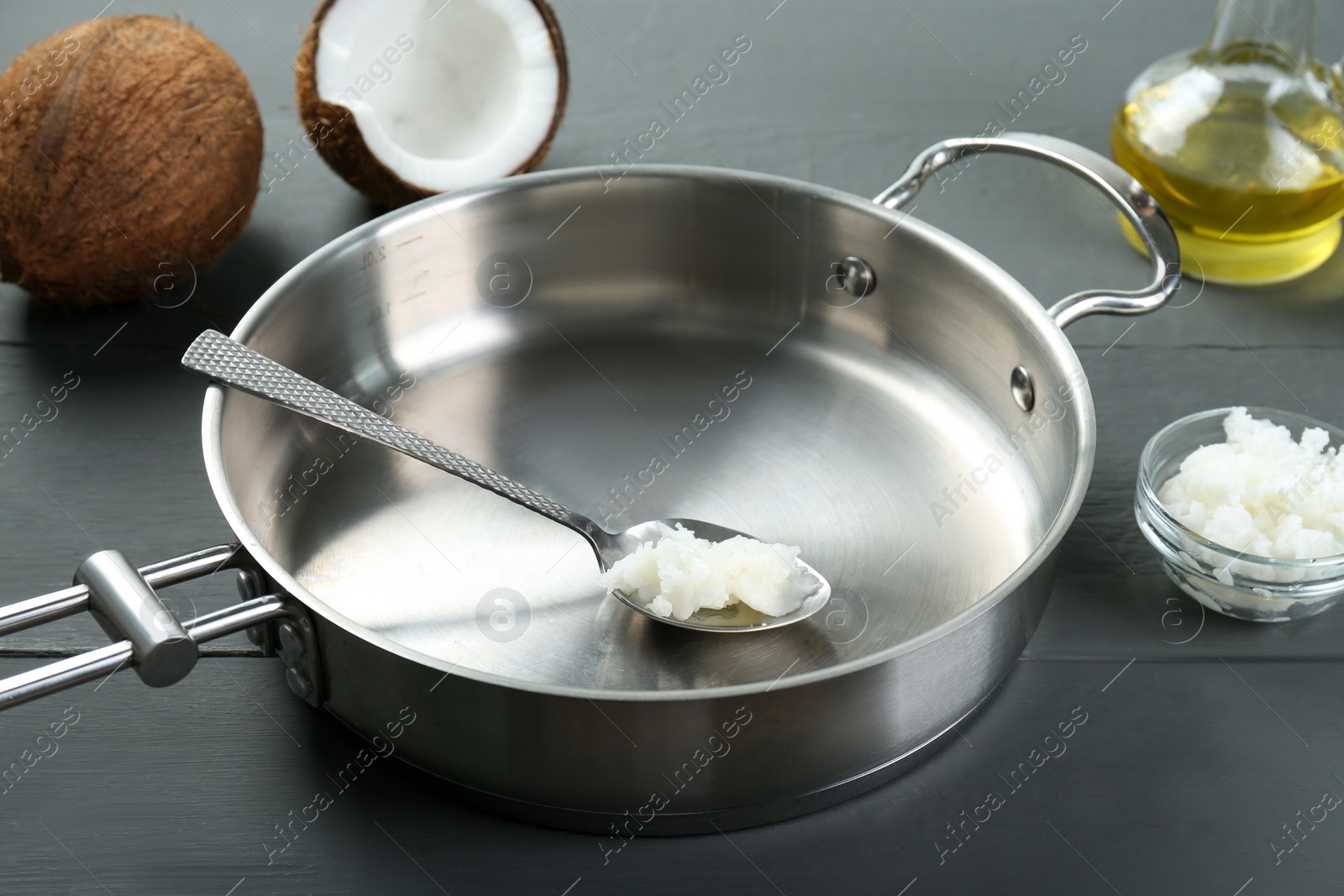 Photo of Frying pan with organic coconut cooking oil and spoon on grey wooden table