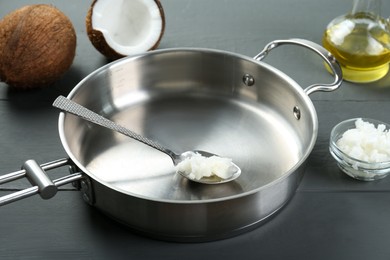 Photo of Frying pan with organic coconut cooking oil and spoon on grey wooden table