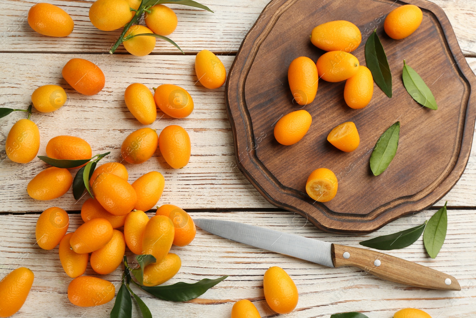 Photo of Fresh ripe kumquats on white wooden table, flat lay