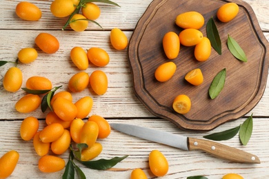 Fresh ripe kumquats on white wooden table, flat lay