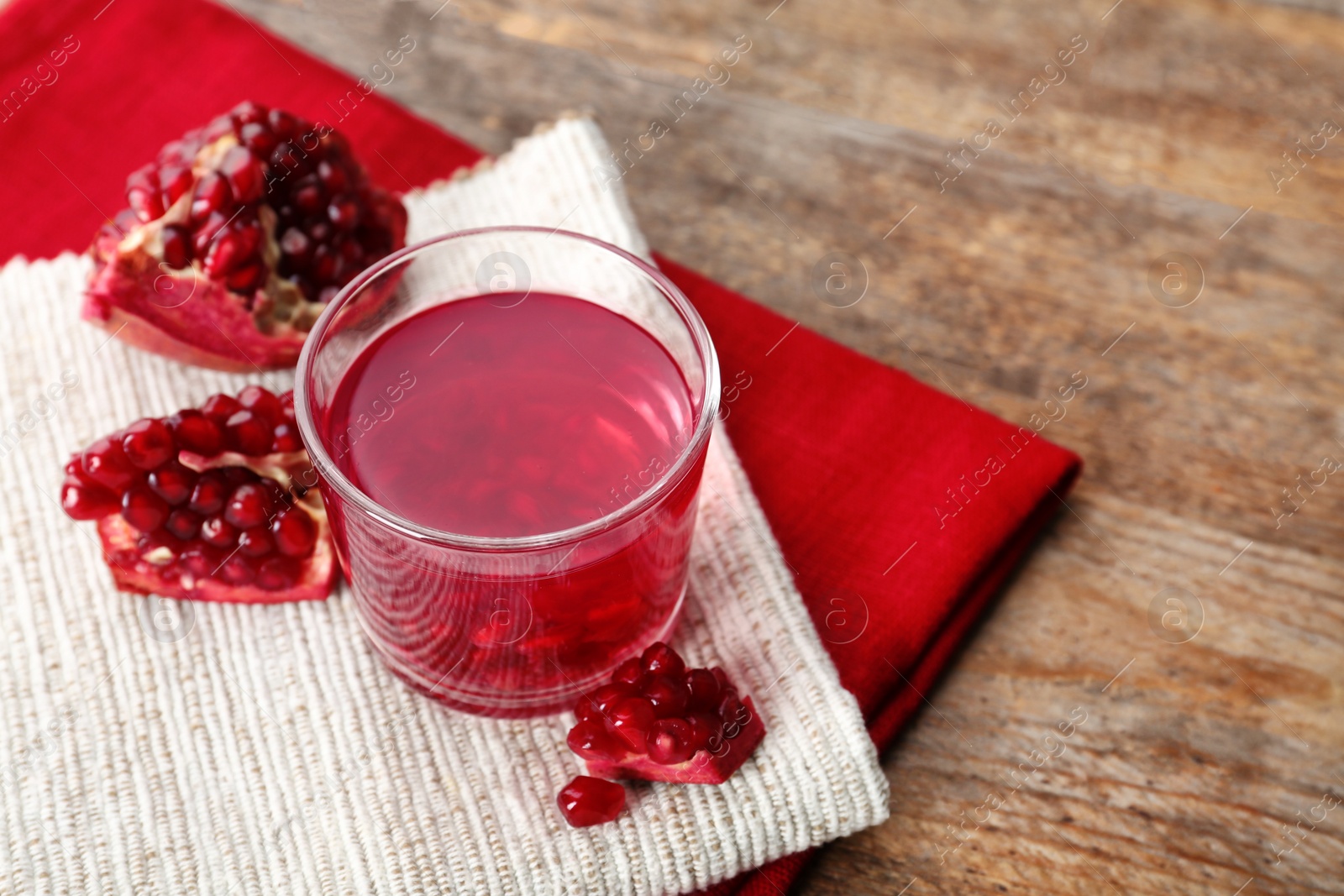 Photo of Glass of pomegranate jelly served on wooden table. Space for text