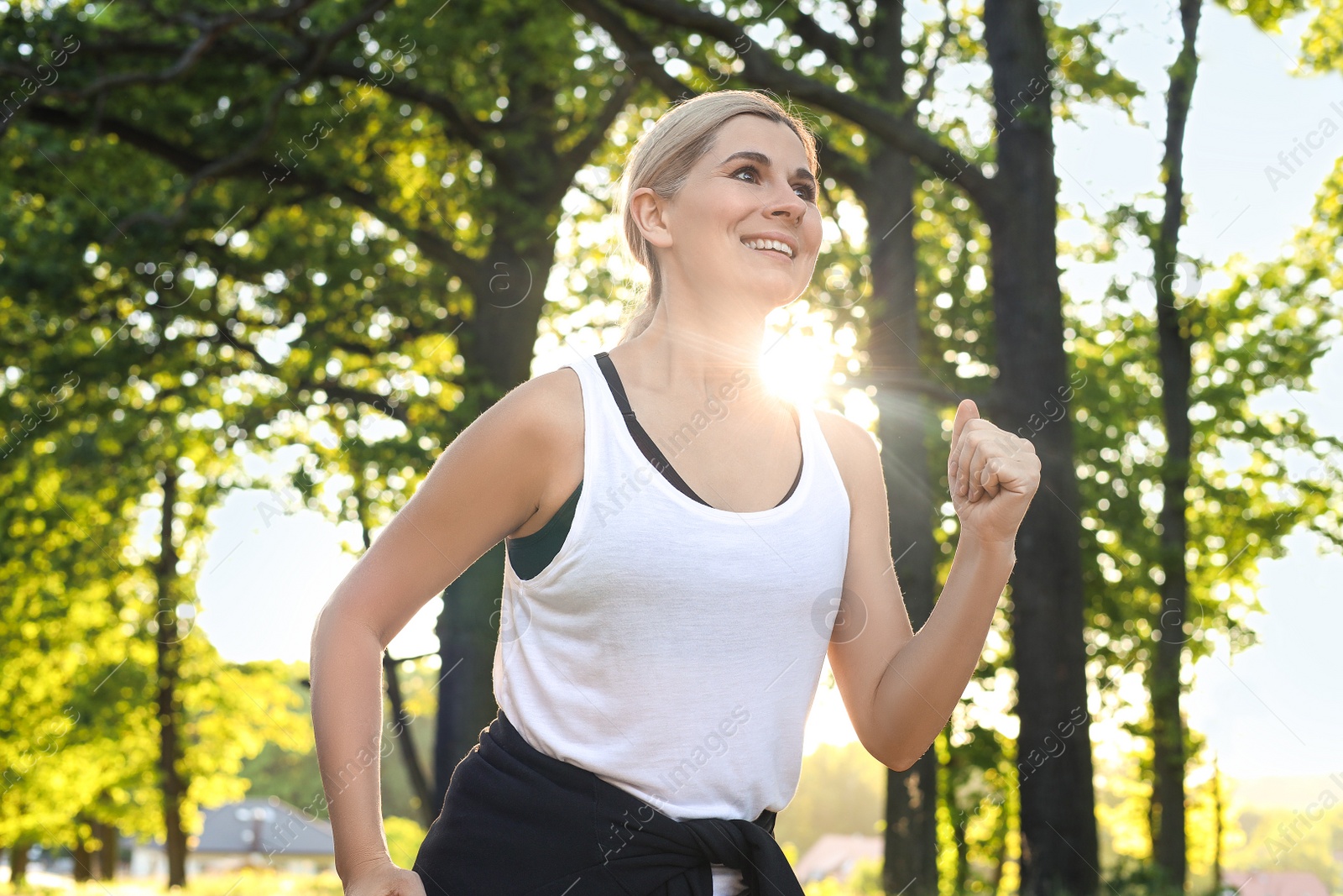 Photo of Woman running in park on sunny day. Healthy morning