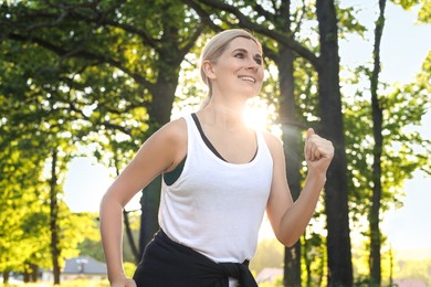 Photo of Woman running in park on sunny day. Healthy morning